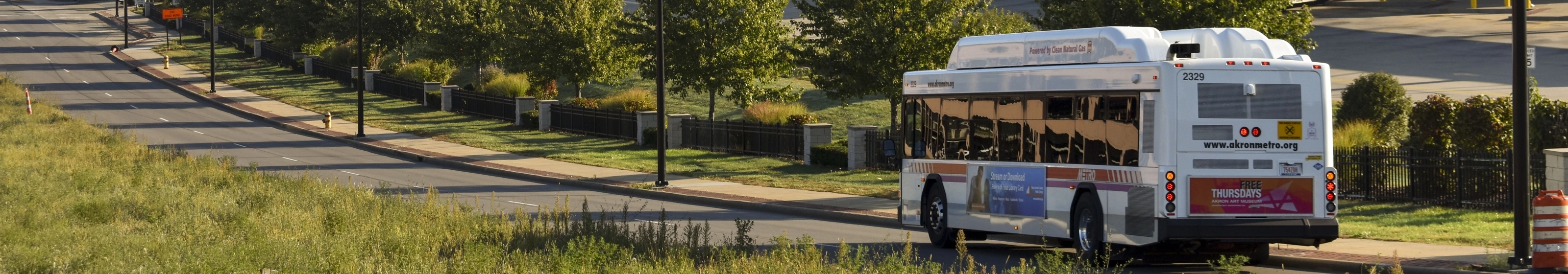 METRO bus driving along a tree-lined road on a sunny day